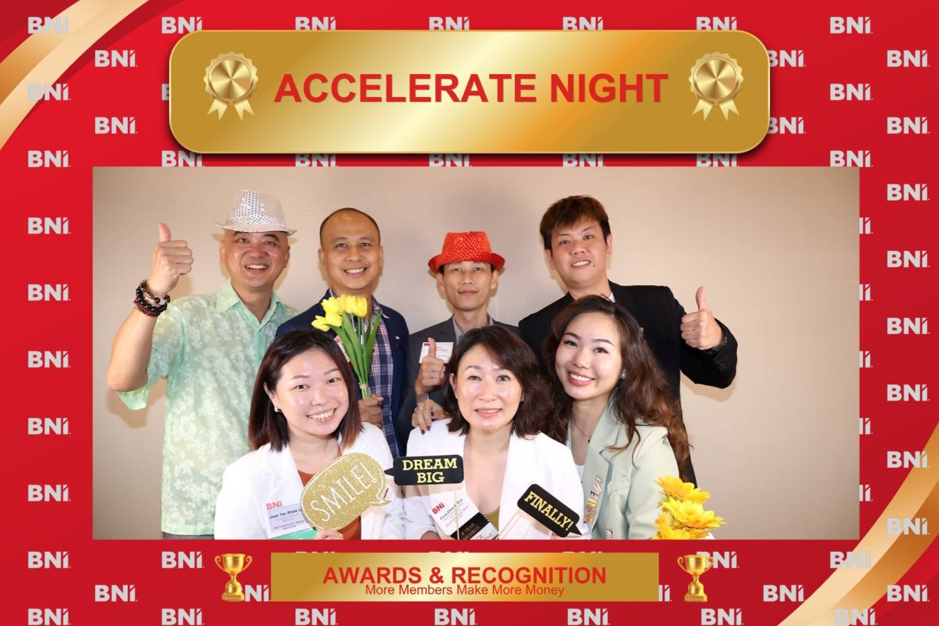 Guests posing with props inside a custom-branded photo booth frame at a corporate awards night